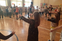 Grupa dzieci tańczy na sali gimnastycznej. 