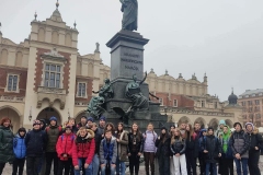 Grupa wycieczkowa na tle Sukiennic pod pomnikiem A.Mickiewicza