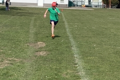 Dziewczynka w czerwonej czapce z dzaszkiem i zielonej koszulce podczas biegu