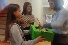Uczennice  podające pudełko życzliwości nauczycielce w celu wylosowania listeczka z życzliwą sentencją