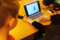 Dzieci i nauczycielka patrzą na obraz wyświetlony na laptopie.