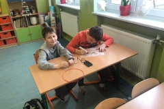 Dwóch chłopców siedzących w ławce, jeden z nich pracuje długopisem 3D