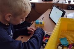 Dwaj chłopcy składają robota z klocków lego prime według instrukcji umieszczonej na tablecie..
