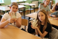 Dziewczynki trzymają w dłoniach  gipsowe odlewy rękaic gumowych
