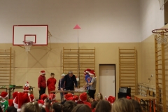 Mężczyzna stoi przy stoliku wraz z trzema chłopcami