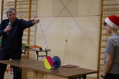 Nauczyciel trzyma sznurek, na końcu którego znajduje się kolorowy walec