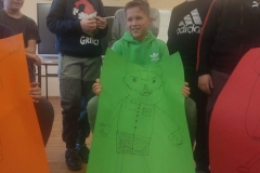 Chłopiec trzyma zielony plakat, za chłopcem stoi grupa uczniów