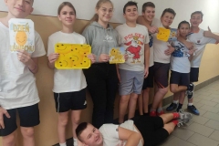 Grupa uczniów na tle białej ściany, niektórzy w rękach trzymają żółte karteczki z narysowanymi uśmiechami