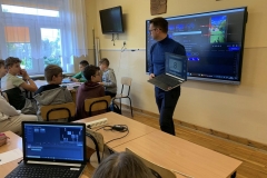 Mężczyzna prezentuje grupie uczniów wyniki pracy jednej z grup na laptopie